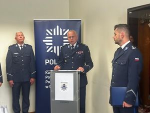 Komendant Wojewódzki policji stojący przy mównicy obok niego dwóch policjantów