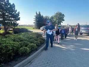 grupka dzieci idąca przez parking za policjantem