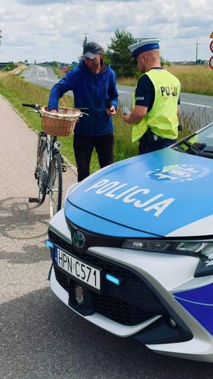 Policjant ruchu drogowego kontrolujący rowerzystą na drodze dla rowerów.