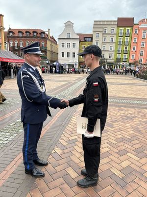 Komendant policji na chojnickim rynku składający gratulacje młodemu mężczyźnie w mundurze