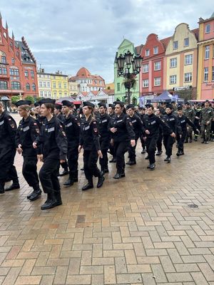 Grupa młodych ludzi w mundurach  idąca w szyku.