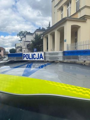 Radiowóz stojący przed budynkiem widoczny napis policja na dachu