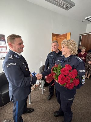 Policjantka wręczająca kwiaty Komendantowi policji w gabinecie.