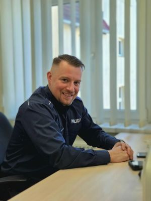 Policjant siedzący przy biurku.