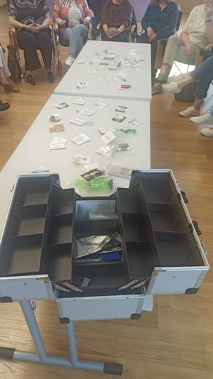 Zdjęcie ze spotkania profilaktycznego podczas którego policjanci prezętują zawartośc walizki edukacyjnej e wktórej znajdują się atrapy narkotykow