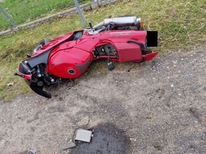 Czerwony motocykl leżący obok płotu