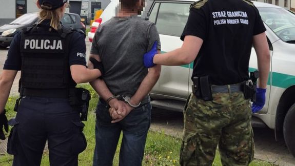 Policjantka i strażnik graniczny prowadzący zatrzymanego