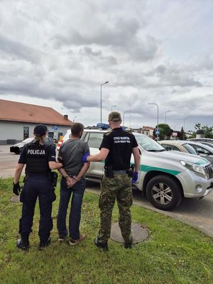 Policjantka oraz strażnik graniczny prowadzący zatrzymanego