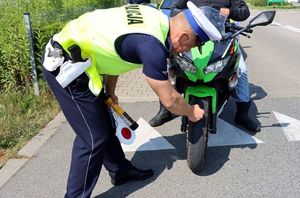 Policjant sprawdzający ogumienie w motocyklu