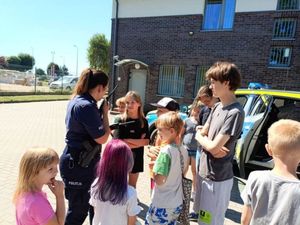 Dzieci na plau wewnętrznym posterunku policji stojące przy radiowozie