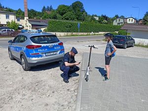 Policjant kontrolujący chłopca na hulajnodze elektrycznej