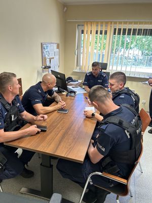 Policjanci siedzący przy stole podczas odprawy służbowej