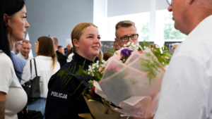 mężczyzna wręczający kwiaty policjnatce podczaś ślubowania