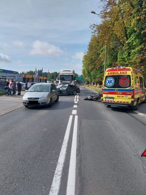 zdjęcie ze zdarzenia drogowego, motocykl leżący na jezdni obo niego stojący pojazdd oraz karetka