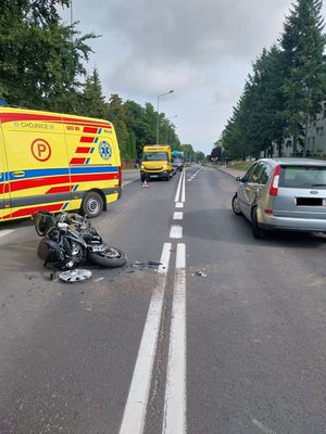 zdjęcie ze zdarzenia drogowego, motocykl leżący na jezdni obo niego stojący pojazdd oraz karetka