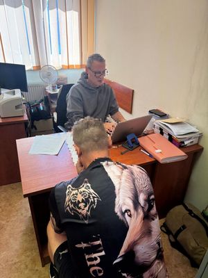 Mężczyzna siedzący przed niemundurowanym policjantem, który siedzi za biurkiem