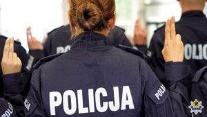 Policjanci stojący tyłem z podniesioną dłonią podczas ślubowania.
