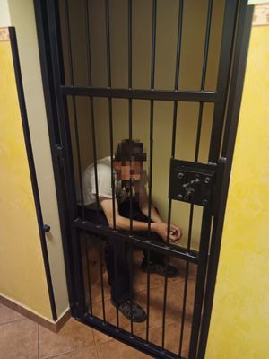 Mężczzyna siedzący w pomieszczeniu za kratą