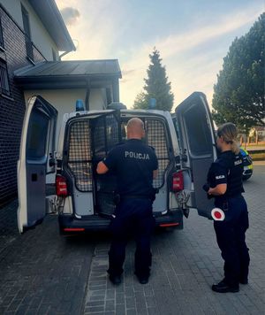Policjanci zamykający drzi do radiowozu w części przeznaczonej dla osób zatrzymanych