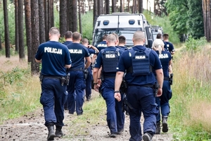 Policjanci idący przez las