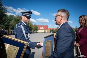Zdjęcia z uroczystości  ślubowania uczniów klas mundurowych. Mężczyzna wręczajacy podziękowania Komendantowi w galowym mundurze.