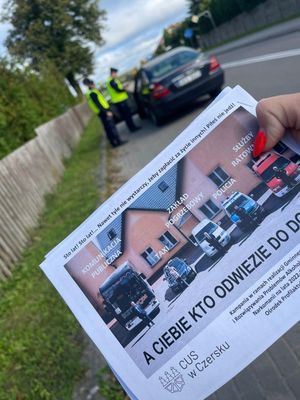 Ulotka kampani przeciw pijanym kierowcą na tle samochodu kontrolowanego przez policjantów.