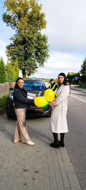 Dwie kobiet z balonami stojące przed kontrolowanym samochodem