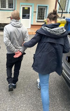 Policjantka prowadząca zatrzymanego przez dziedziniec
