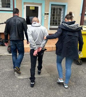 Policjanci prowadzący zatrzymanego przez dziedziniec