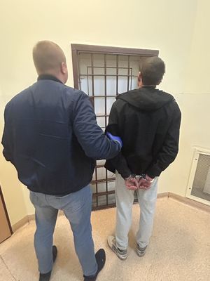 Nieumiundurowany policjant z zatrzymanym stojący przy kracie