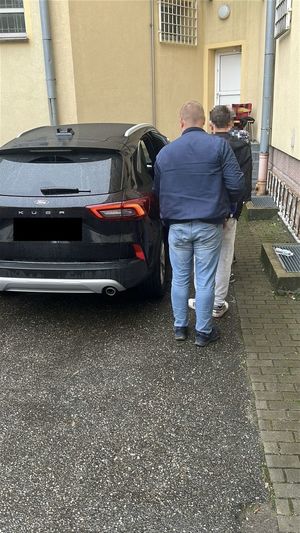 Policjanci prowadzący zatrzynmanego do radiowozu