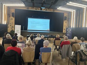 Zdjęcie ze spotkania policjantów z seniorami w Brusach na sali widowiskowej seniorzy siedzący na krzesłach przed policjantami i wysłuchujący prelekcji