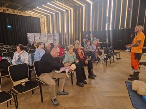 Zdjęcie ze spotkania policjantów z seniorami w Brusach na sali widowiskowej seniorzy siedzący na krzesłach przed policjantami i wysłuchujący prelekcji