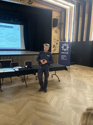 Zdjęcie ze spotkania policjantów z seniorami w Brusach na sali widowiskowej seniorzy siedzący na krzesłach przed policjantami i wysłuchujący prelekcji