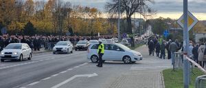 Policjant stojący na skrzyżowaniu wokół po chodnikach idą grupy ludzi