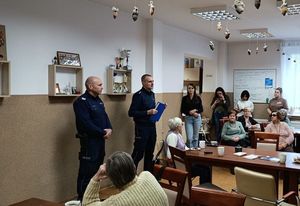 Policjanci podczas debaty stojący przed seniorami siedzącymi przy stołach