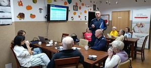 Policjanci podczas debaty stojący przed seniorami siedzącymi przy stołach