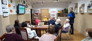 Policjanci podczas debaty stojący przed seniorami siedzącymi przy stołach