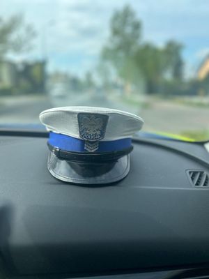 Czapka policjanta ruchu drogowego leżąca na kokpicie w radiowozie