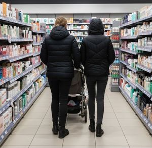 obraz wygenerowany przez sztuczną inteligęcje przedstawiający dwie kobiety prowadzące wózzek w drogeri.