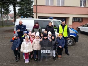 Policjanci podczas spotkania z dziećmi przed radiowozem pozujący do zdjęcia