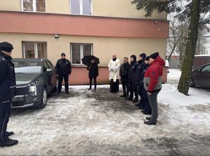 Policjanci umundurowani stoją przy nieoznakowanym radowozie