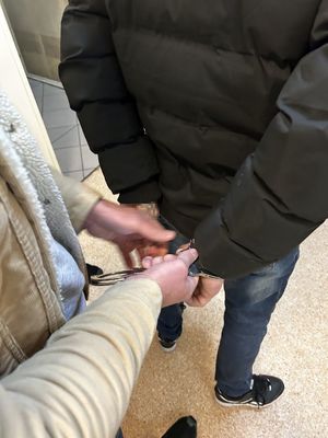 Policjant skuwwający w kajdanki zatrzymanego mężczyznę