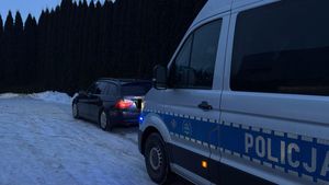 Policyjny radiowóz stojący za samochodem osobowym