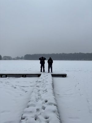Policjant wraz z innym mężczyzną stojący na zaśnieżonym mostu nad jeziorem