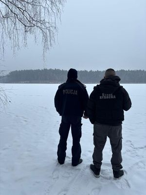 Policjant wraz i mężczyzną stojący na zaśniezonym akwenie