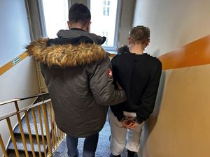 Policjanci prowadzący zatrzymanego po schodach