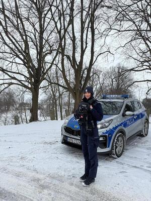 Policjantka stojąca przy radiowozie w zimowej sceneri