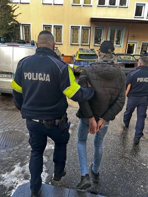 Policjanci prowadzący zatzrymanego do radiowozu