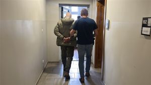 Policjant prowadzący przez korytarz zatrzymanego